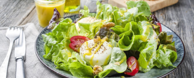 Traditional Germen summer lettuce with curled lettuce, goat cheese and mango as closeup on a plate on a well laid table